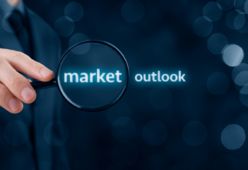 Businessman's hand holding magnifying glass to market outlook