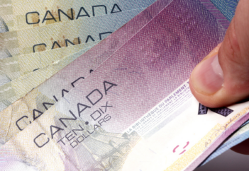 Thumb holding assorted Canadian dollar bills