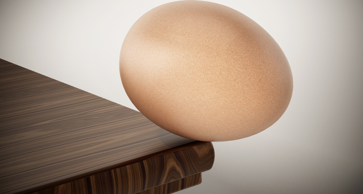 Egg teetering on edge of table