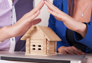 Man and woman touching fingertips over little wooden house
